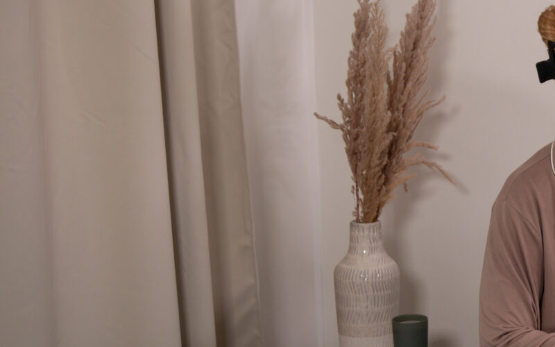 Yöpukuun pukeutunut henkilö istuu sängyllä peiton alla levollisen näköisenä.