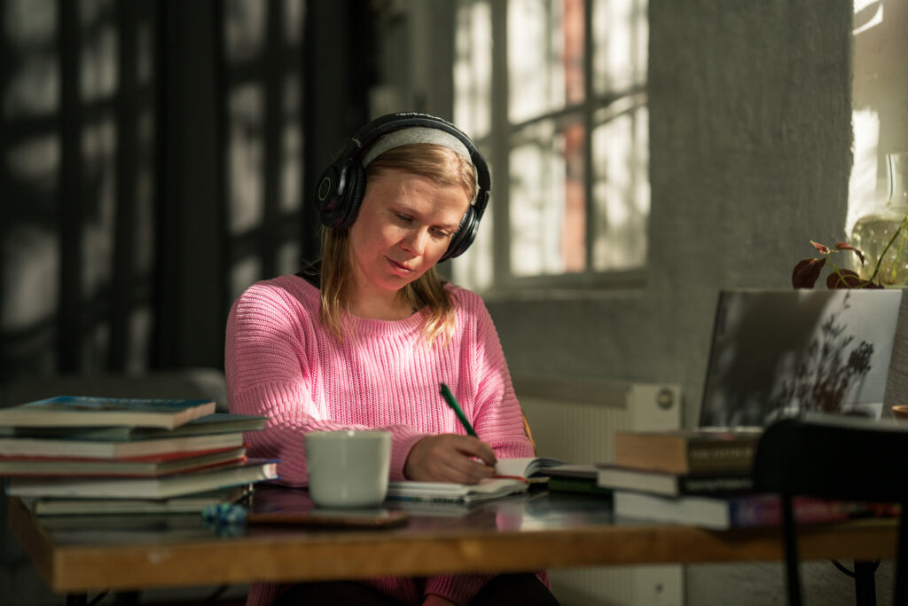 A student with headphones is studying at a desk.