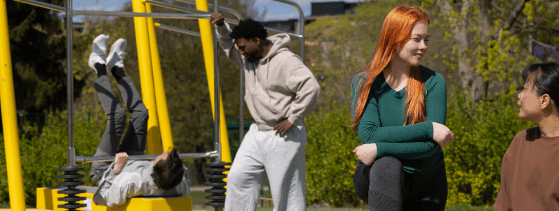 Neljä opiskelijaa urheilemassa ulkoliikuntapaikalla.